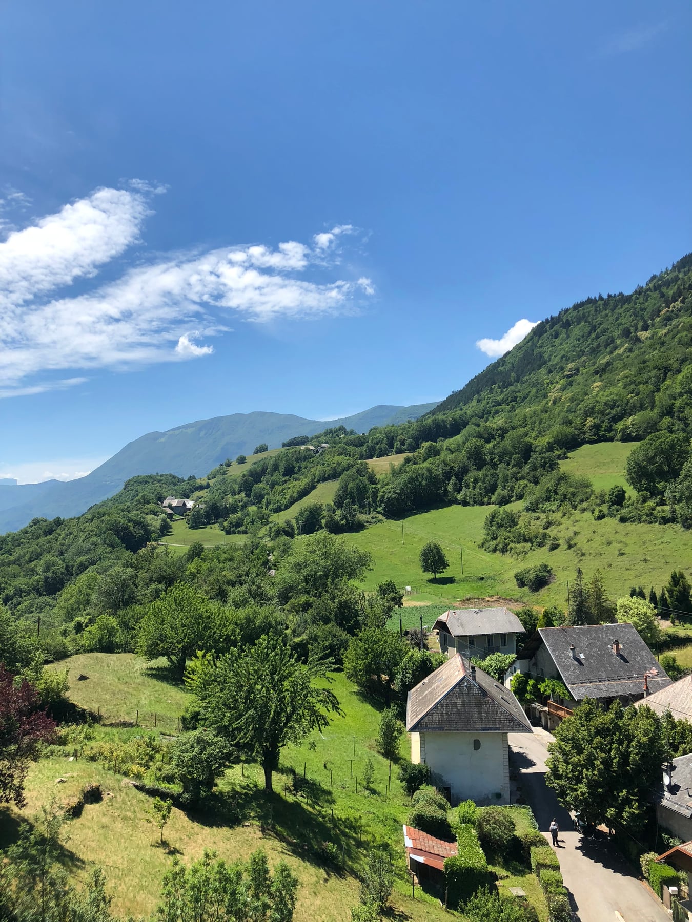 Green mountain slopes and rural homes beneath a bright blue sky