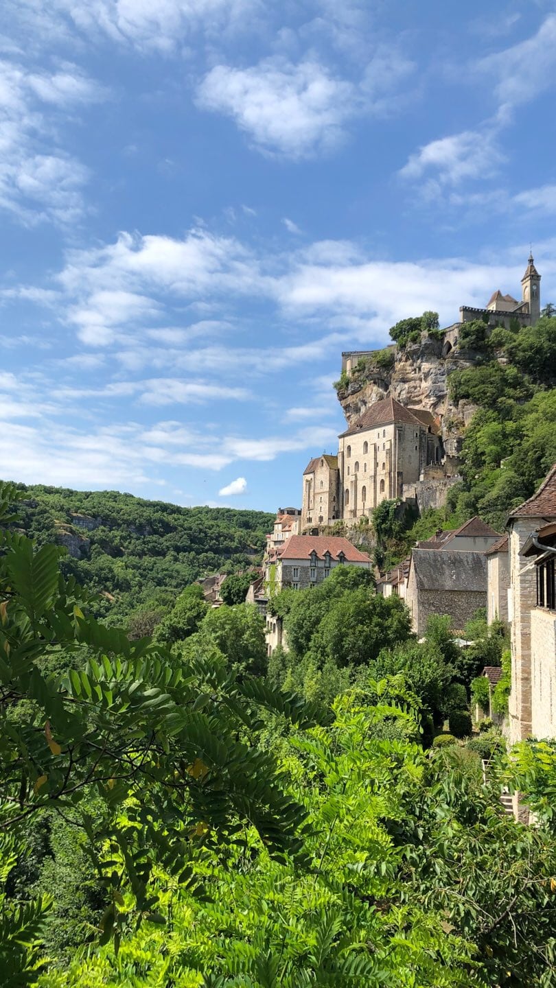 Historic stone buildings rising above a green French hillside