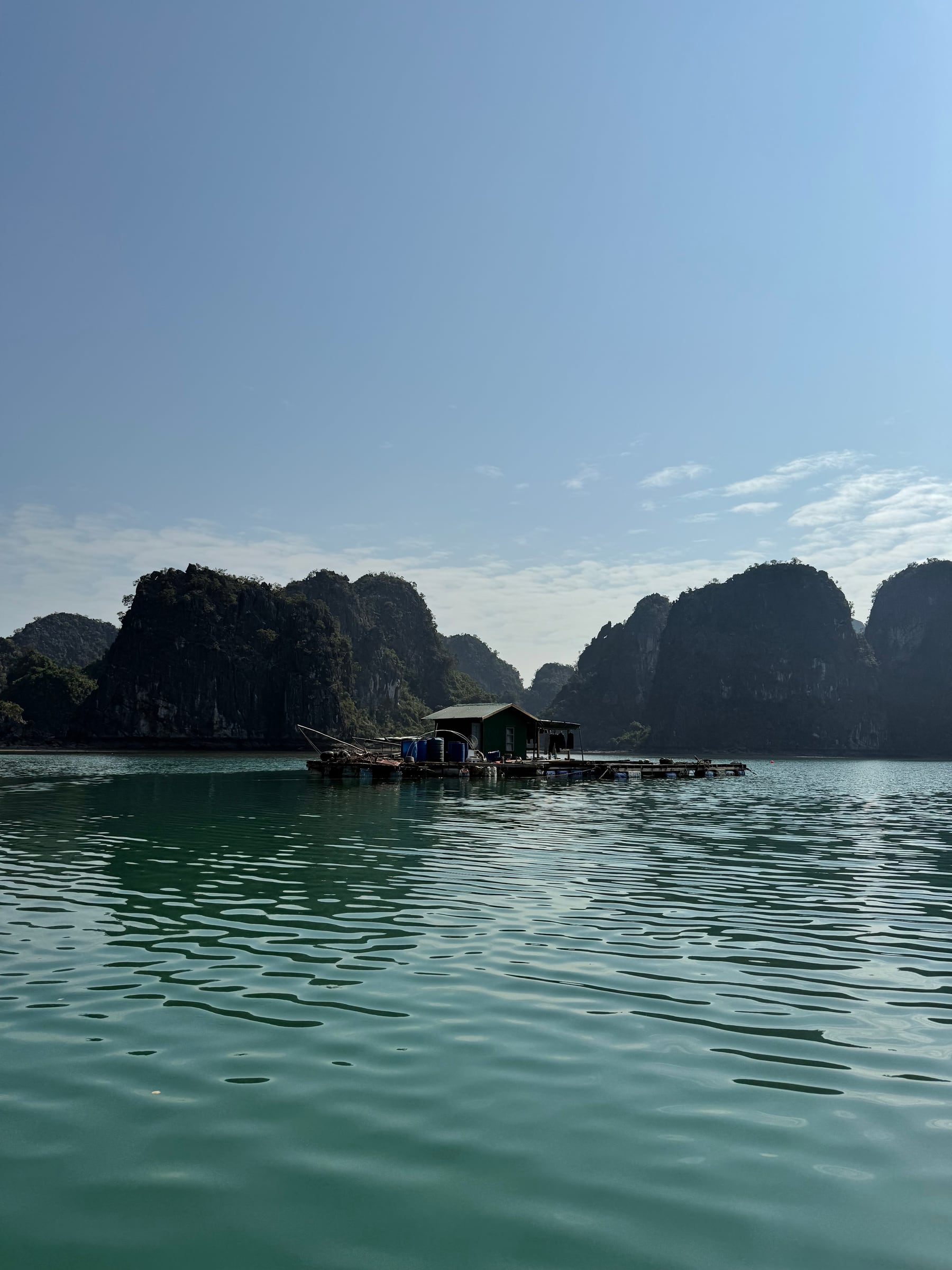 Floating house on calm water beneath limestone karsts in Vietnam