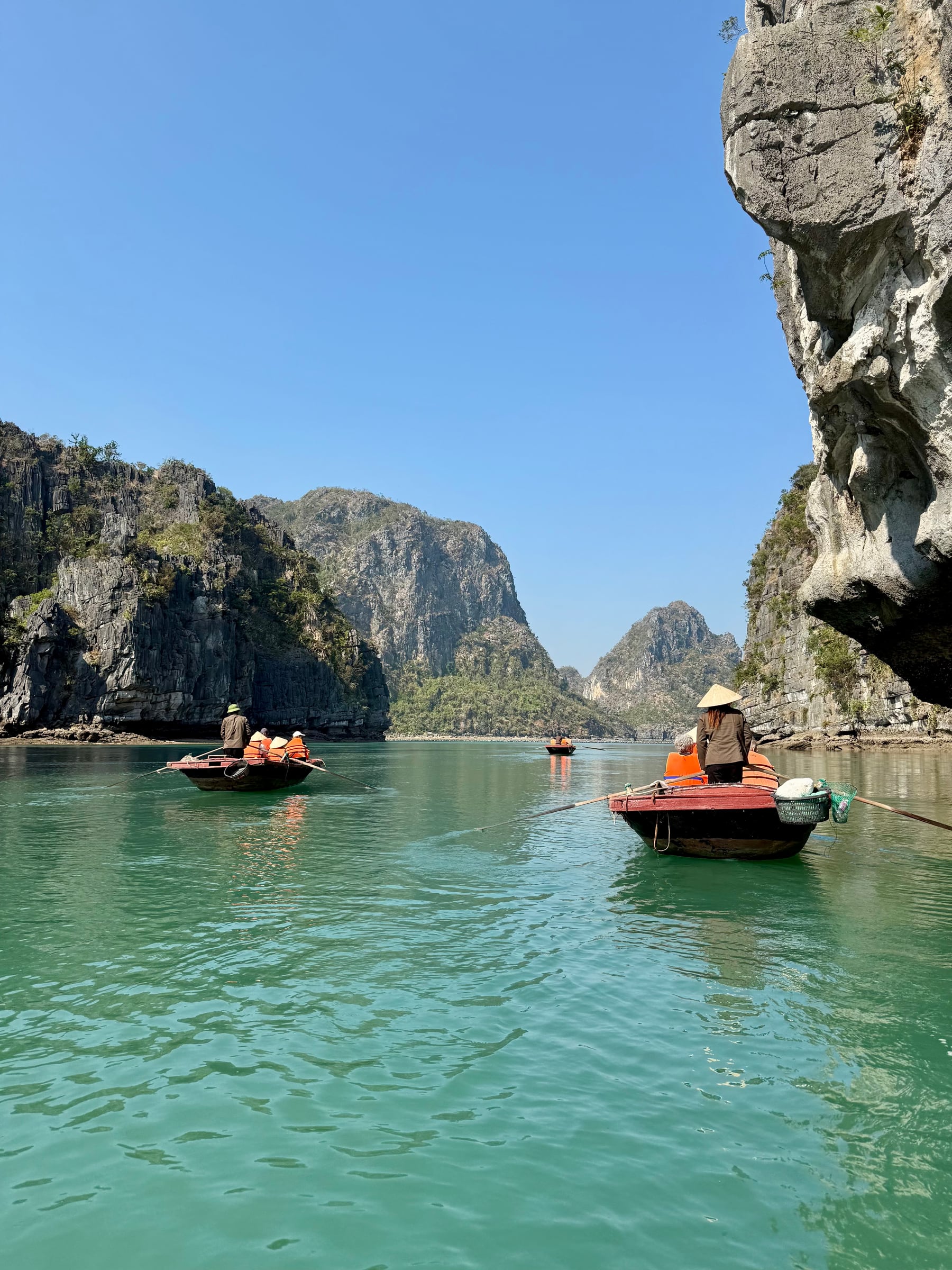 Rowboats crossing turquoise water between limestone cliffs