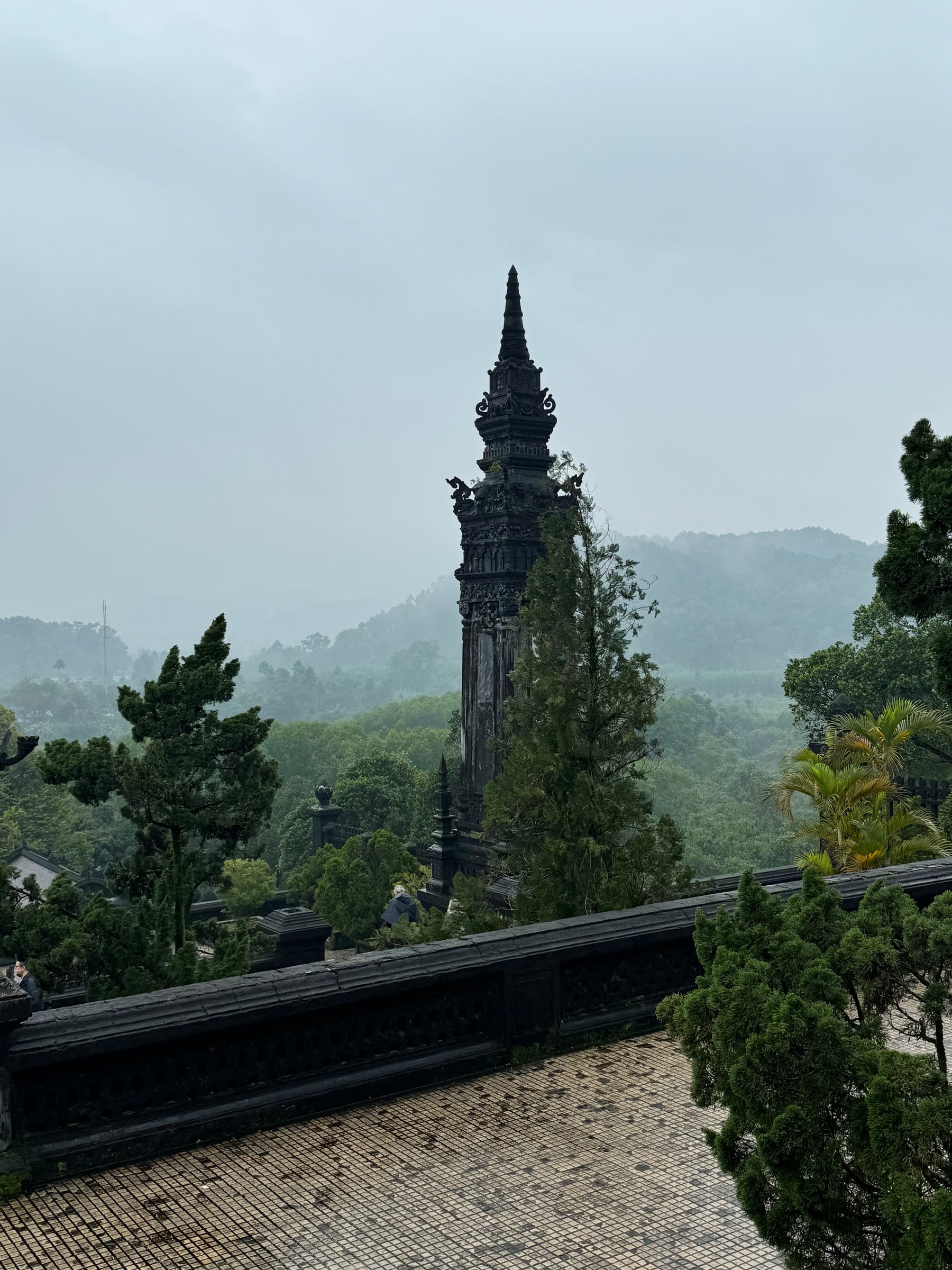 Dark stone monument rising above a green, misty hillside